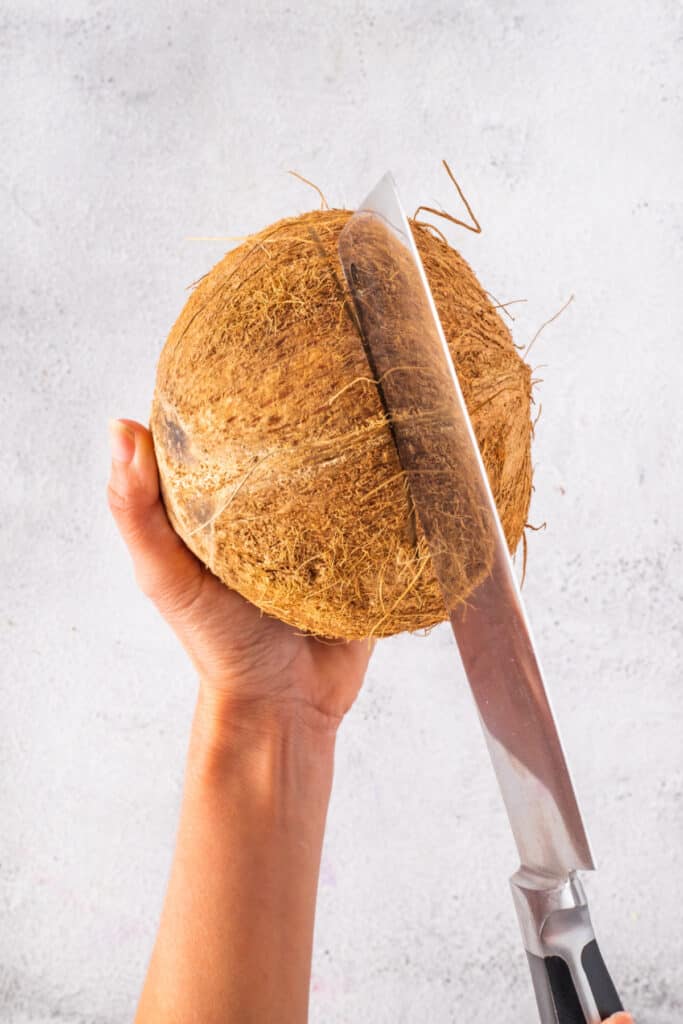 Scoring a fresh coconut before splitting it into serving bowls for Halo Halo.