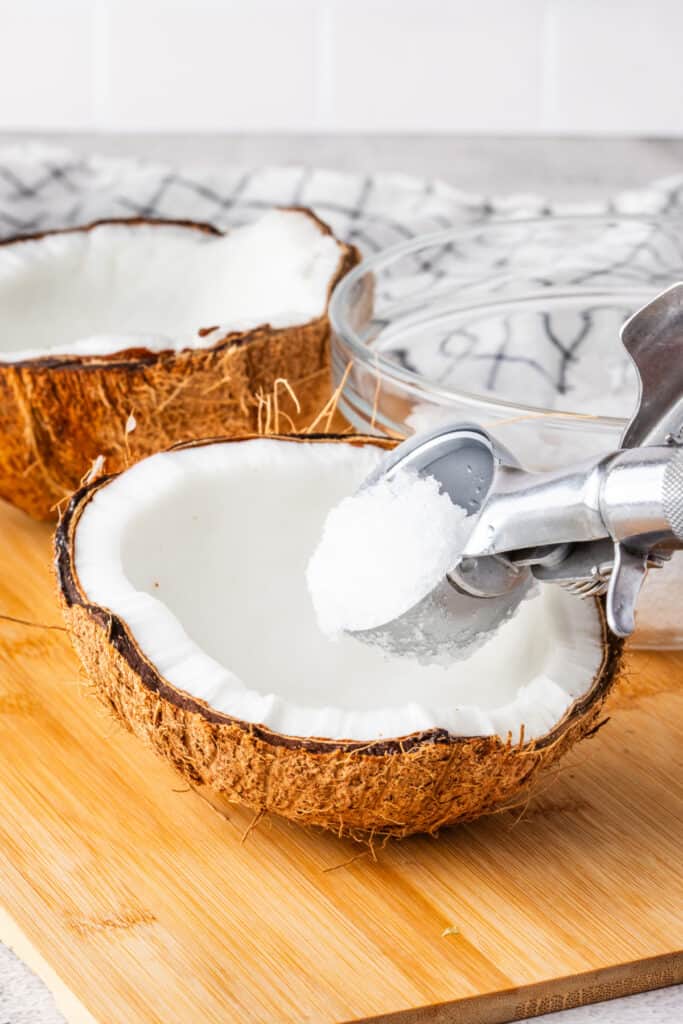 Adding shaved ice to a fresh coconut shell for homemade Halo Halo.
