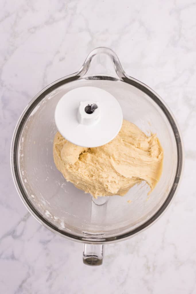 Homemade hamburger bun dough kneading in a stand mixer with a dough hook