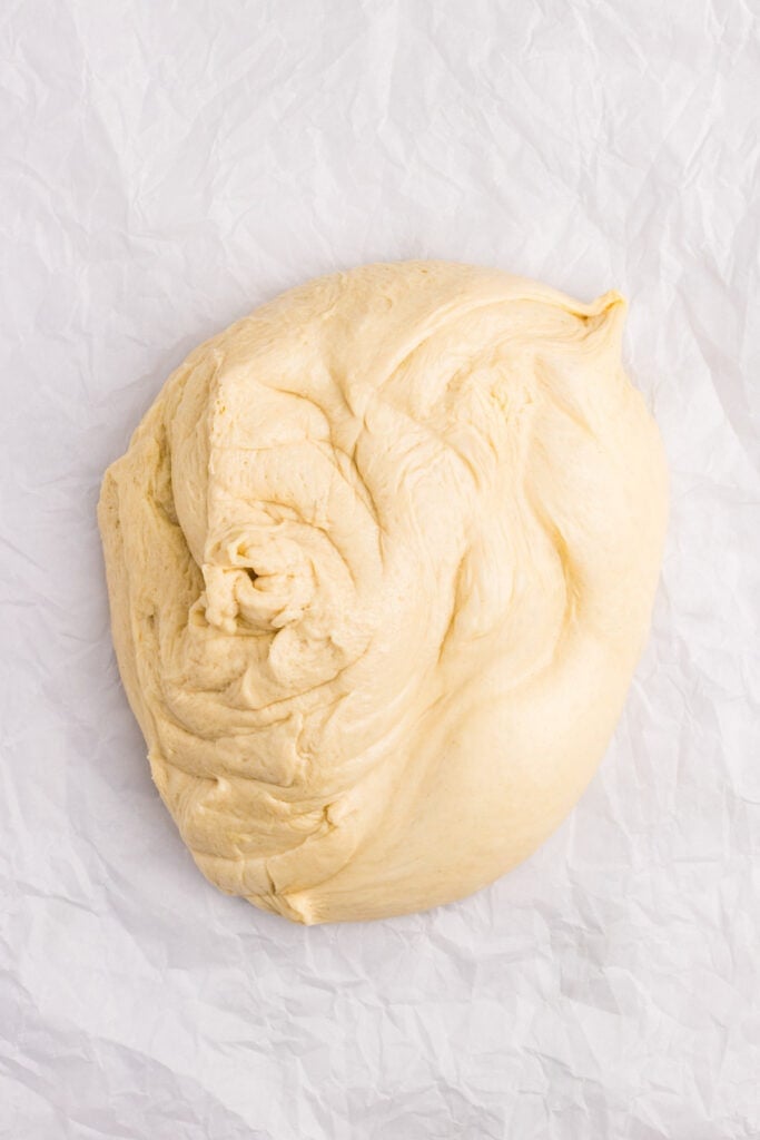 Homemade hamburger bun dough turned onto parchment paper after rising