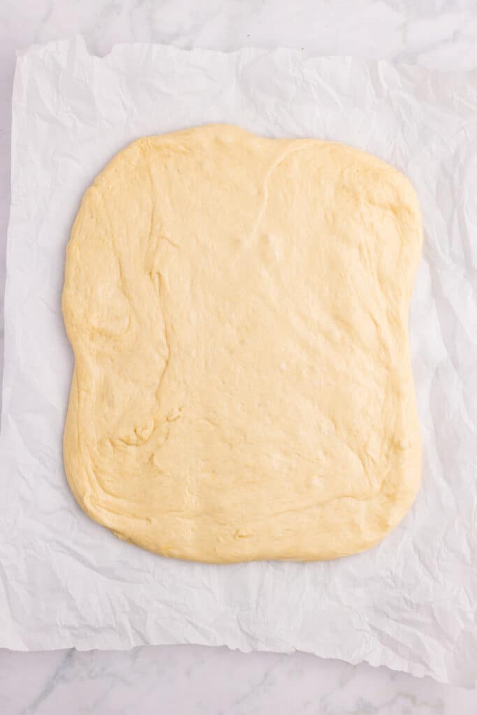 Homemade hamburger bun dough gently pressed into a large rectangle