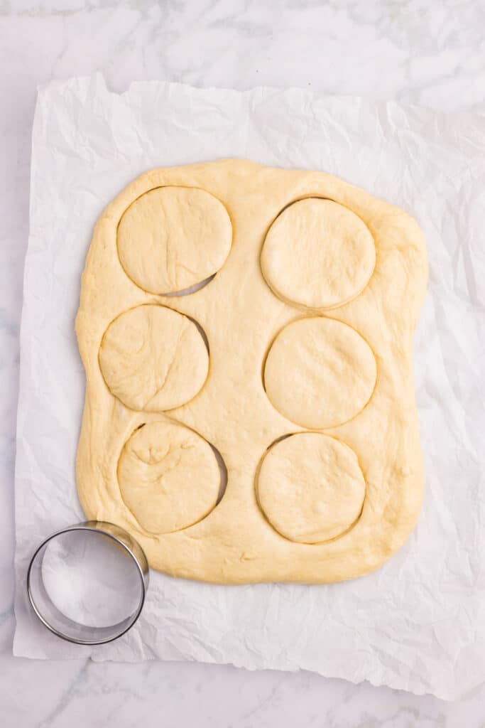 Cutting homemade hamburger buns from rolled dough with a round cutter