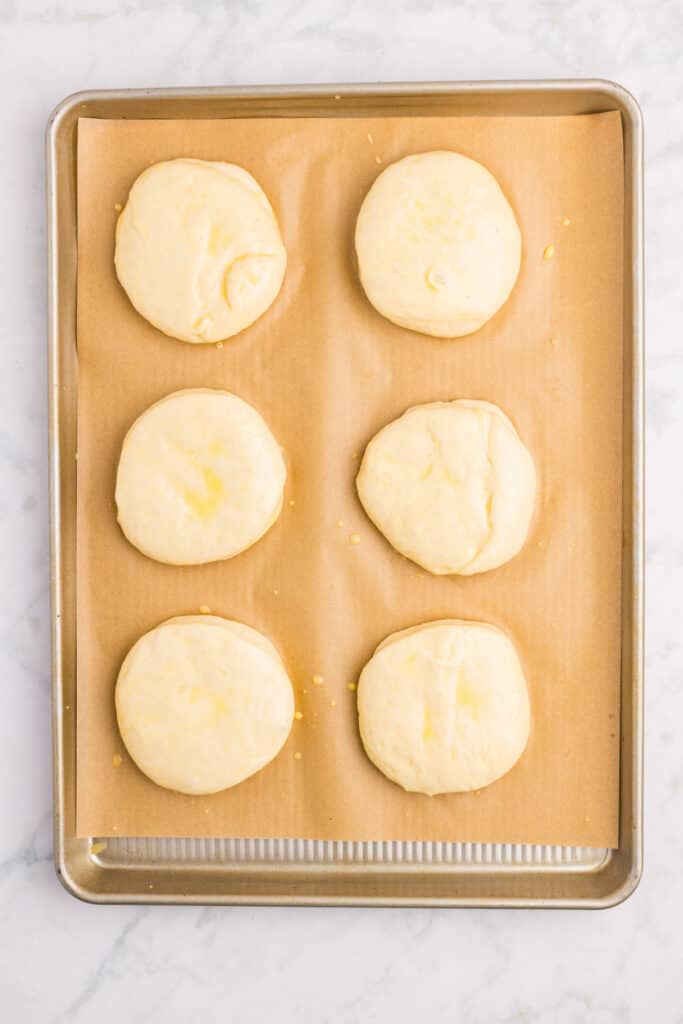 Homemade hamburger buns brushed with egg wash and ready for sesame seeds