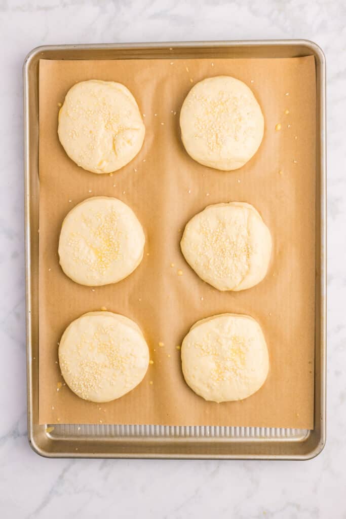 Sesame seeds sprinkled over homemade hamburger buns before baking