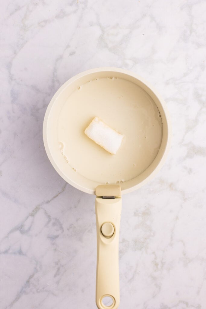 Milk, butter, sugar, and salt warming in a saucepan for hamburger bun dough