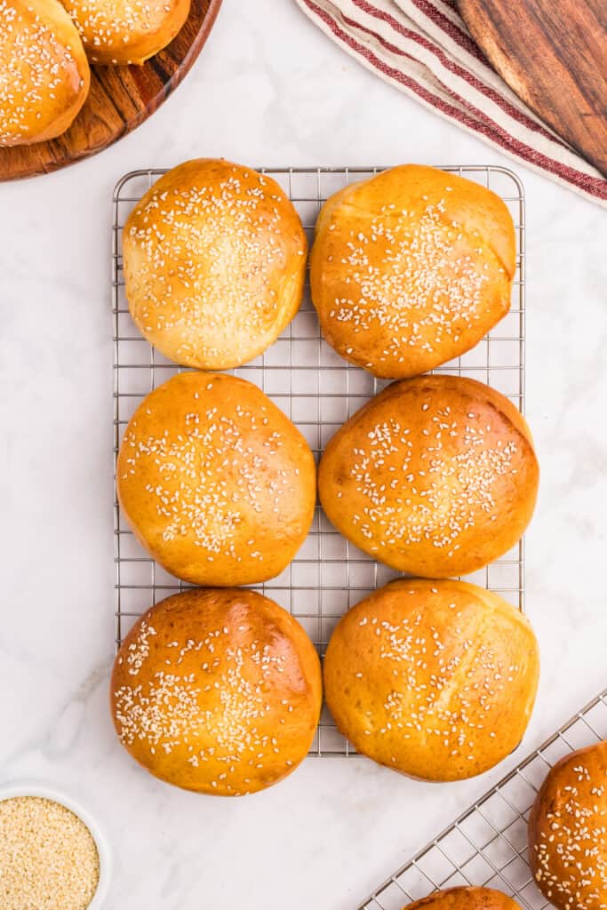 Homemade hamburger buns cooling on a wire rack after baking