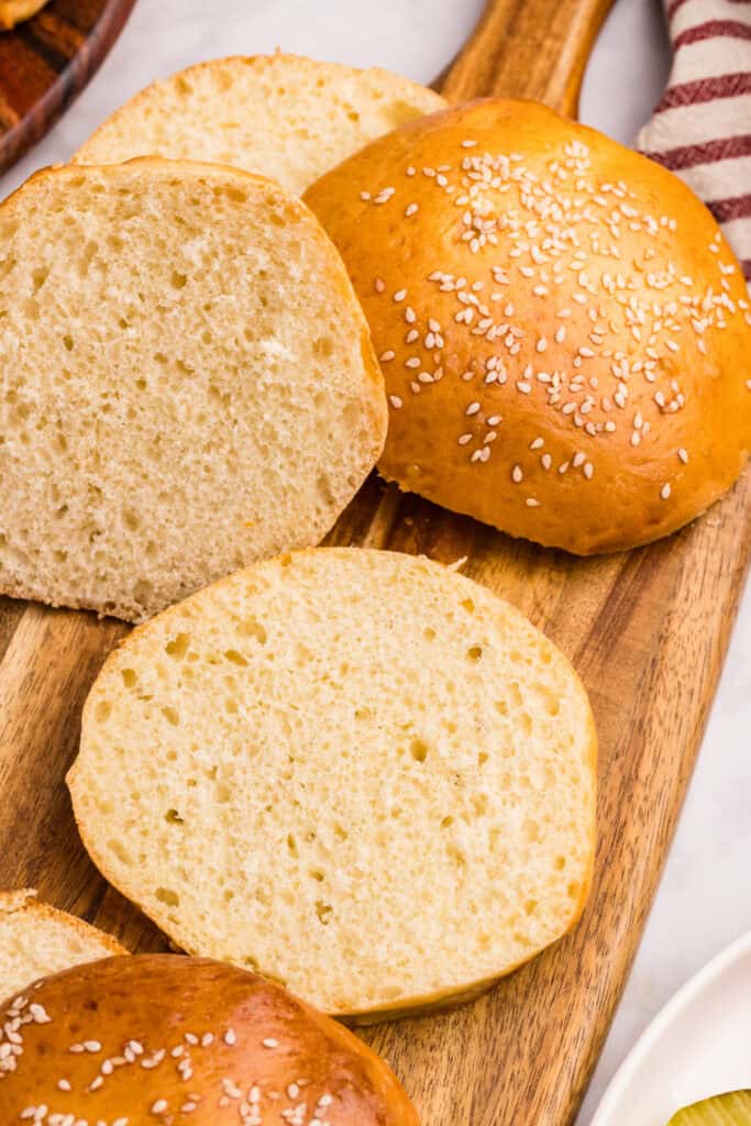 Homemade hamburger buns on a wooden serving board ready for burgers