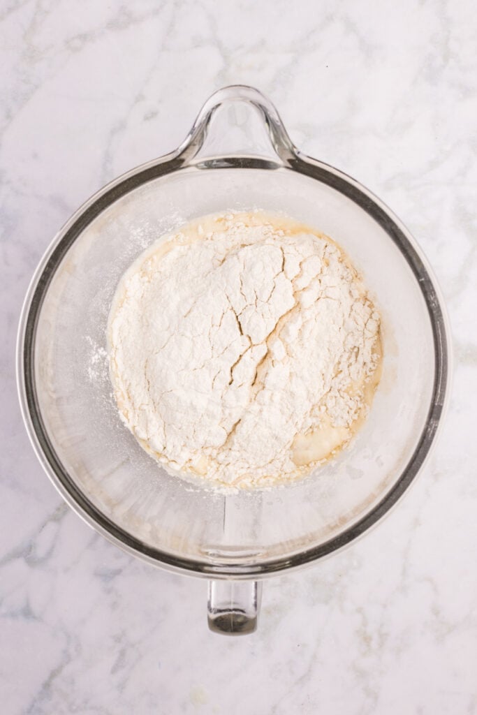 Flour added to the wet ingredients to begin making hamburger bun dough