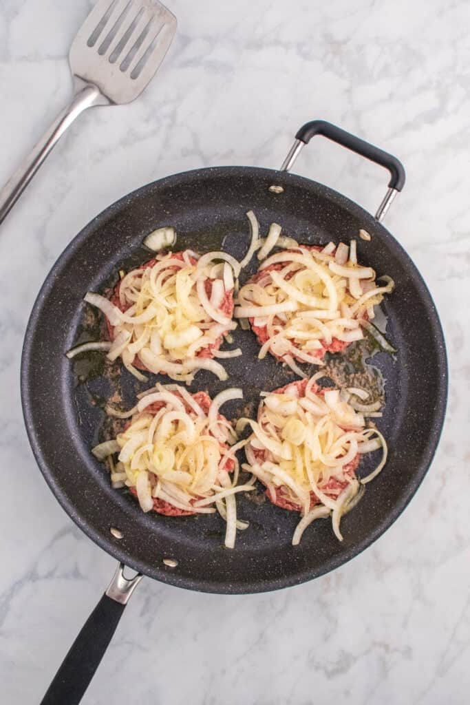 Thinly sliced onions piled onto smashed burger patties.