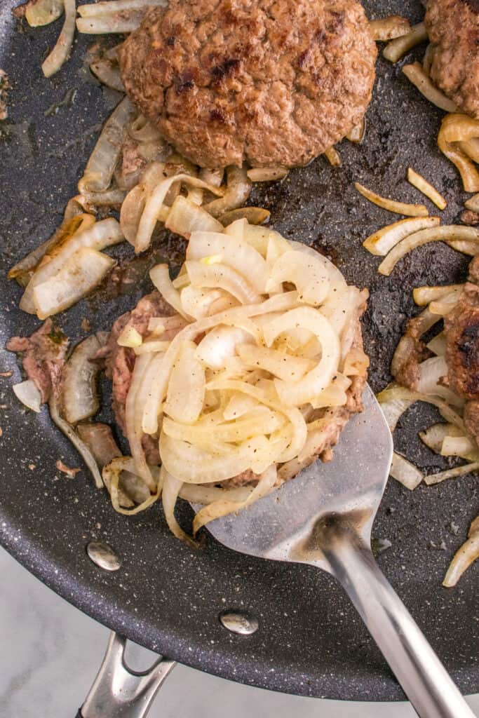 Flipping an Oklahoma Onion Burger with caramelized onions attached.