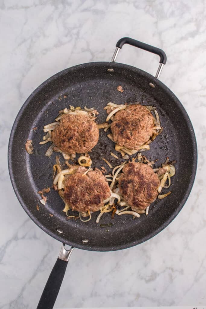 Oklahoma Onion Burgers cooking with onions underneath the patties.