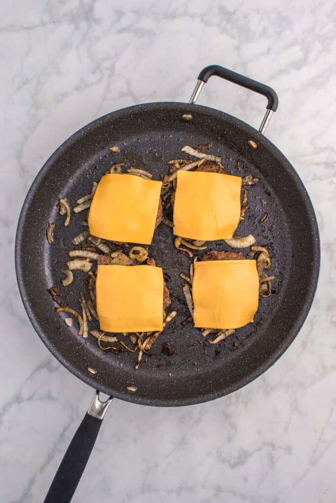 American cheese melting over Oklahoma Onion Burgers.