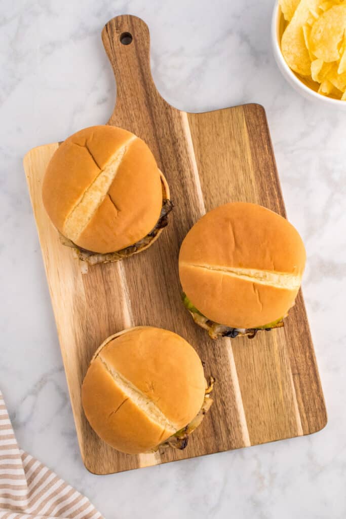 Oklahoma Onion Burgers on a wooden serving board.