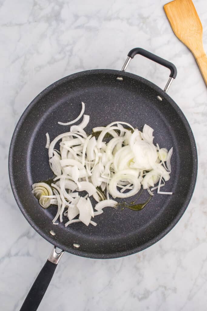 Thinly sliced onions cooking in a skillet.
