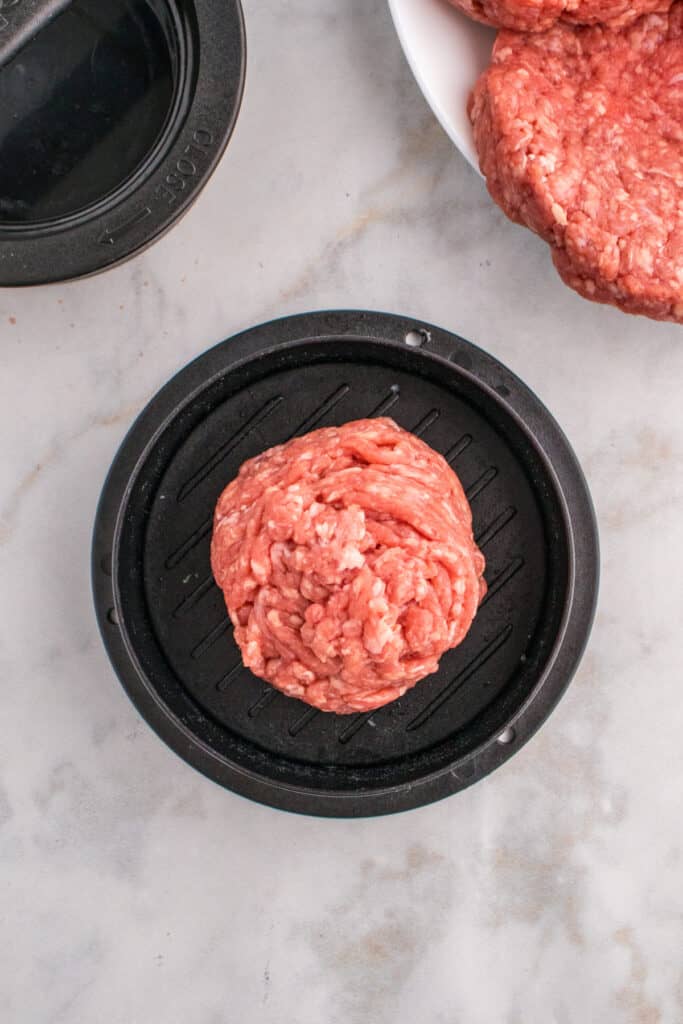 Ground beef ball placed in a burger press.
