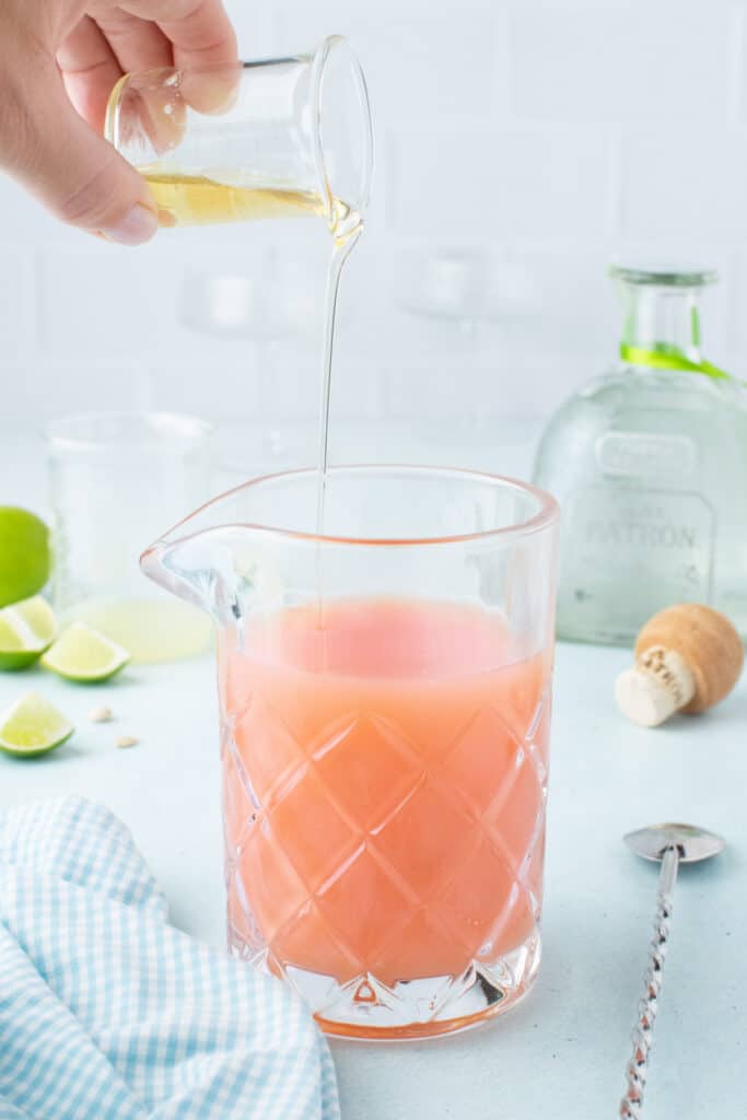 Adding agave syrup to fresh grapefruit juice while making a Paloma Cocktail.
