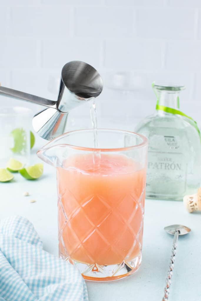Pouring tequila into a mixing glass with fresh citrus for an easy Paloma Cocktail.