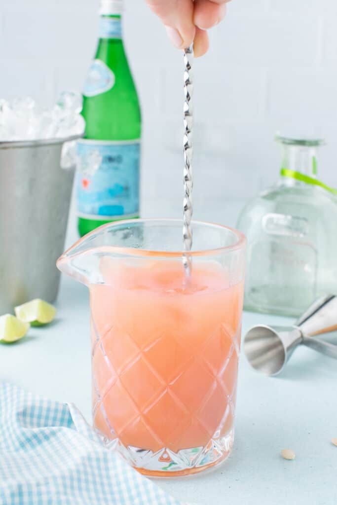Stirring a homemade Paloma Cocktail with ice before serving.