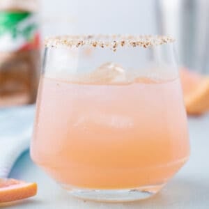 Close-up of a refreshing Paloma Cocktail served over ice with a Tajín rim.