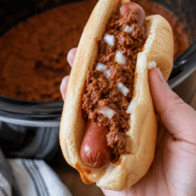 Homemade chili dog topped with Slow Cooker Hot Dog Chili in a square food photo.