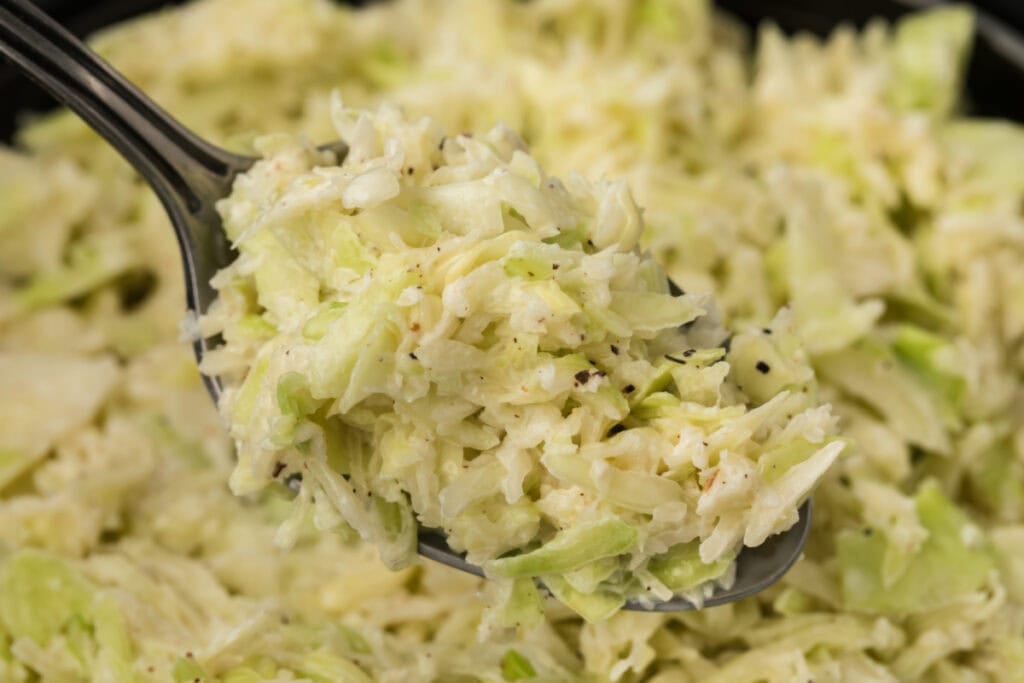 Spoonful of creamy Southern-Style Slaw served above a bowl of homemade coleslaw.