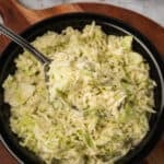 Southern-Style Slaw served in a black bowl with a spoonful of creamy homemade coleslaw lifted above the dish.
