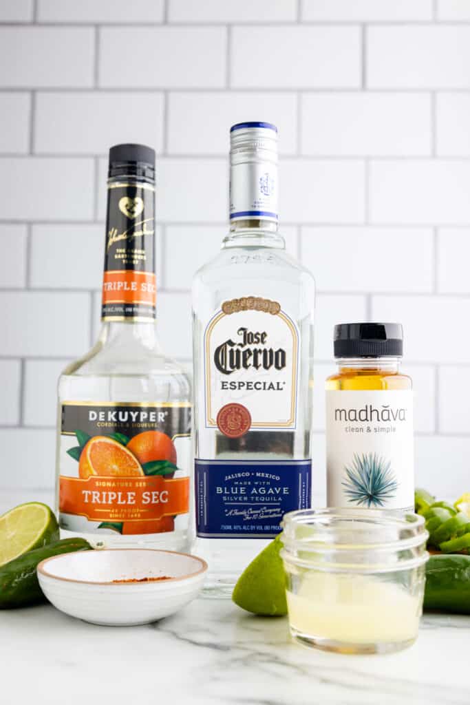 Ingredients for a spicy margarita recipe including blanco tequila, triple sec, fresh lime juice, agave nectar, and jalapeños