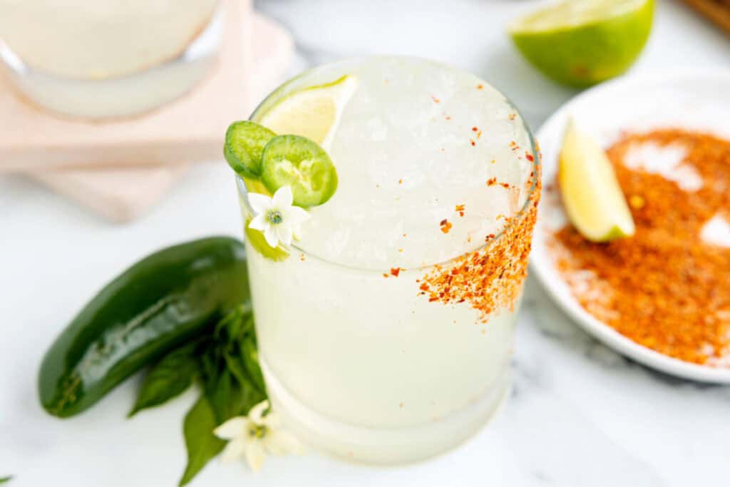 Homemade spicy margarita with fresh jalapeño slices, lime wedge, and a Tajín rim ready to serve