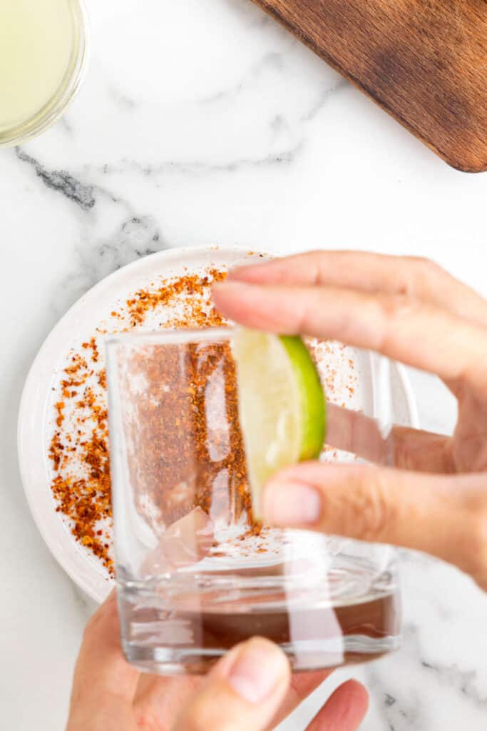 Rubbing a lime wedge around the rim of a rocks glass before dipping it in Tajín