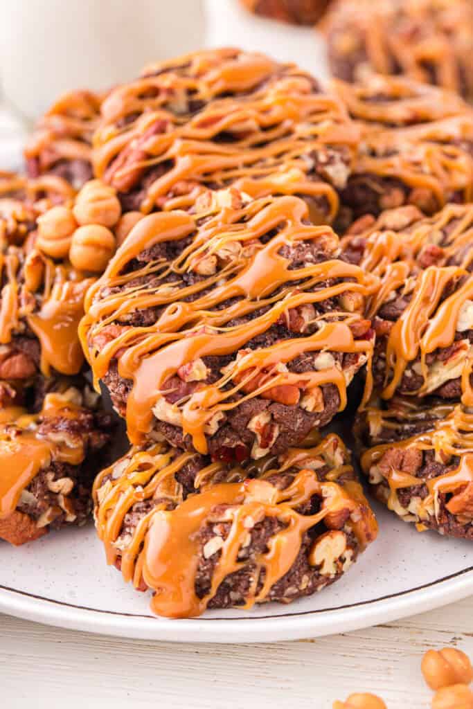 Close-up of Easy Turtle Cookies topped with chopped pecans and a generous caramel drizzle.