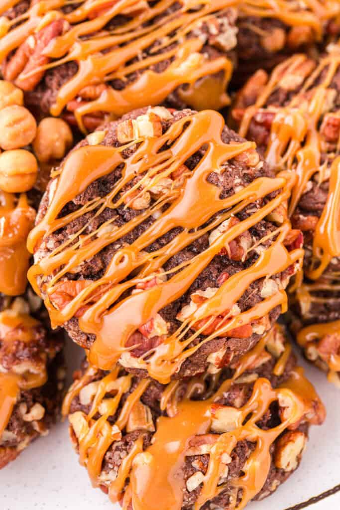 Close-up of Easy Turtle Cookies topped with chopped pecans and a generous caramel drizzle.