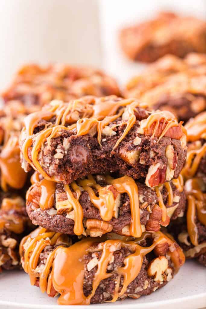Stack of Easy Turtle Cookies drizzled with caramel on a serving plate.