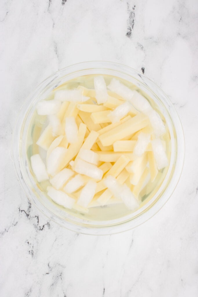 Fresh-cut potato fries soaking in a bowl of ice water before air frying
