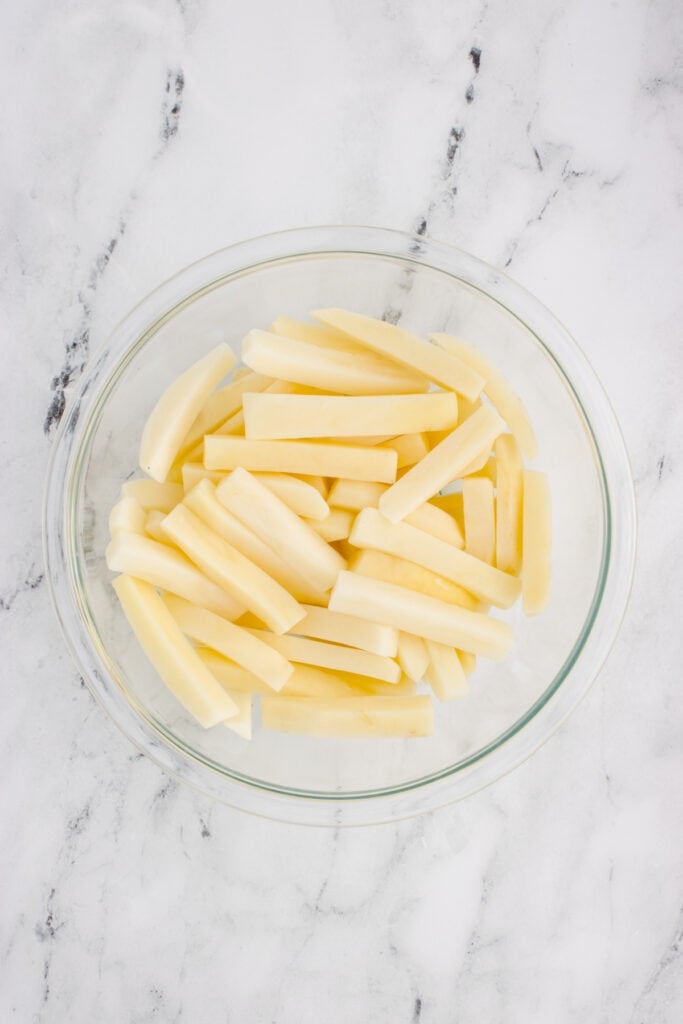 Soaked potato fries drained and ready to be thoroughly dried before seasoning