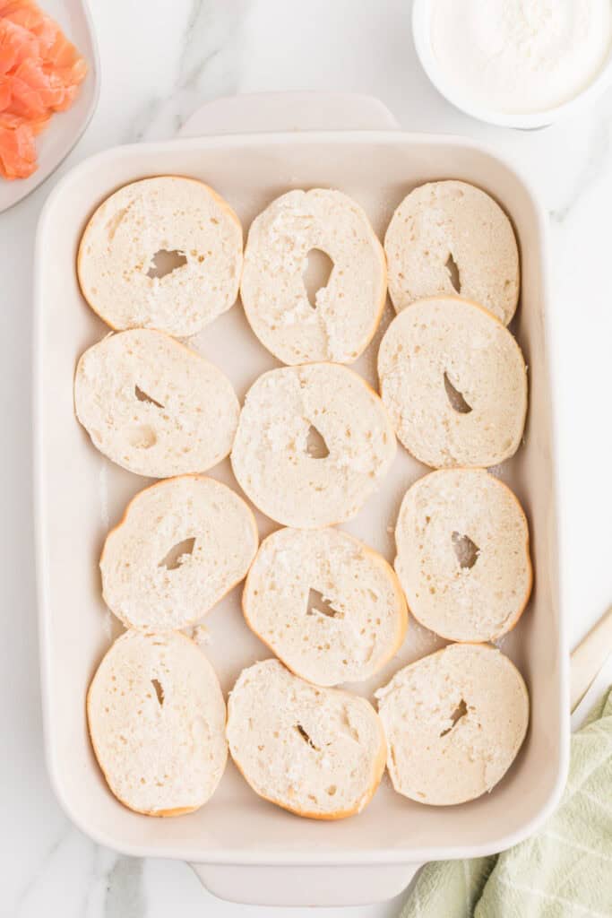 Sliced mini bagel bottoms arranged in a 13x9-inch baking dish