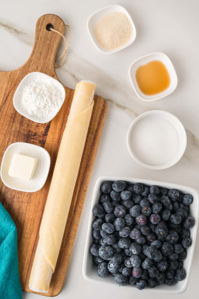 Ingredients for homemade Blueberry Galette including fresh blueberries, pie crust, sugar, cornstarch, vanilla, and butter