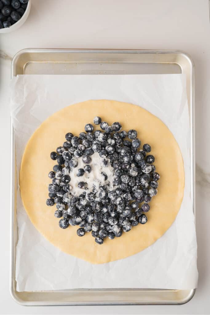 Blueberry filling arranged in the center of refrigerated pie crust on a parchment-lined baking sheet