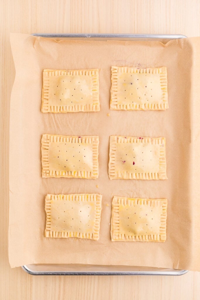 Unbaked homemade Pop-Tarts sealed and crimped with a fork on a baking sheet
