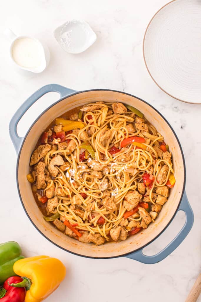 Linguine cooked with seasoned chicken, tomatoes, and colorful bell peppers in a Dutch oven