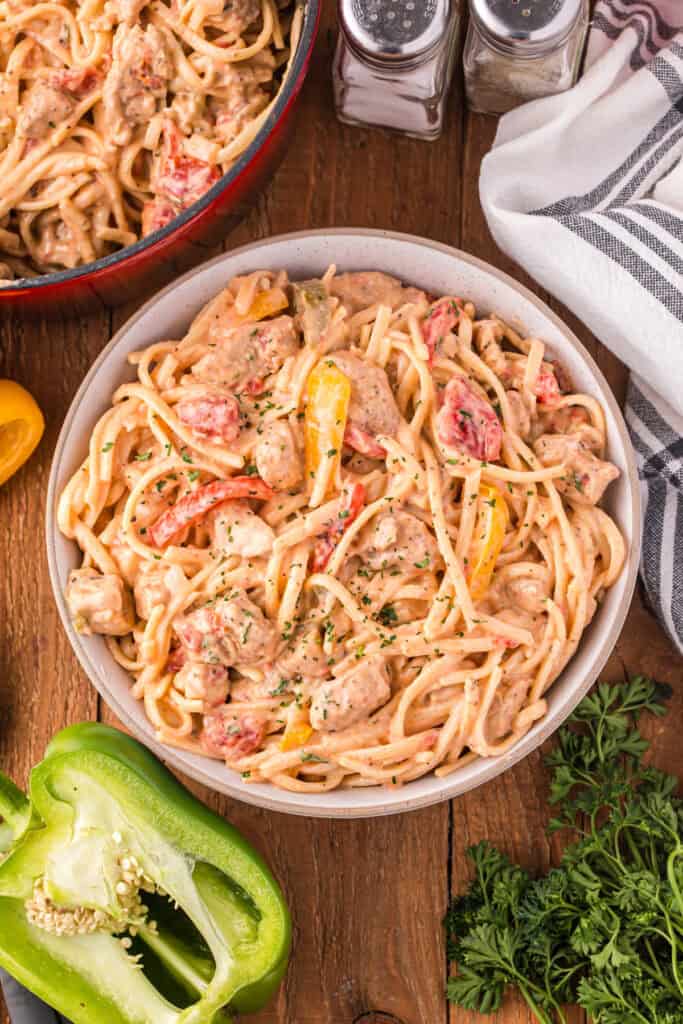 Bowl of creamy Cajun pasta with chicken, linguine, red and yellow peppers, tomatoes, and parsley