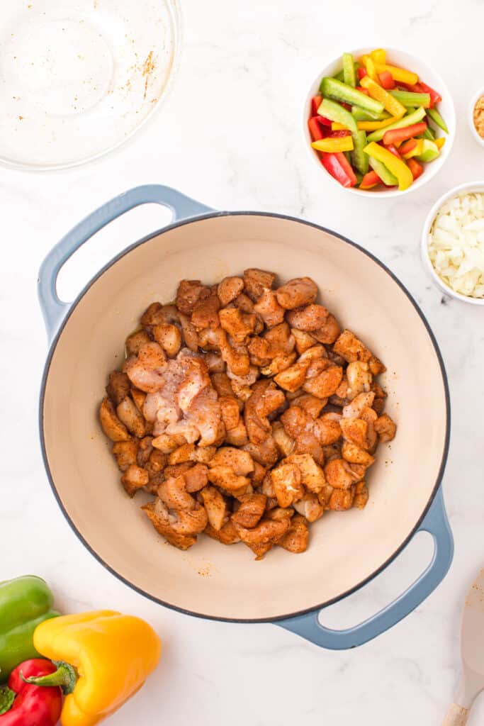 Seasoned chicken breast pieces searing in a Dutch oven