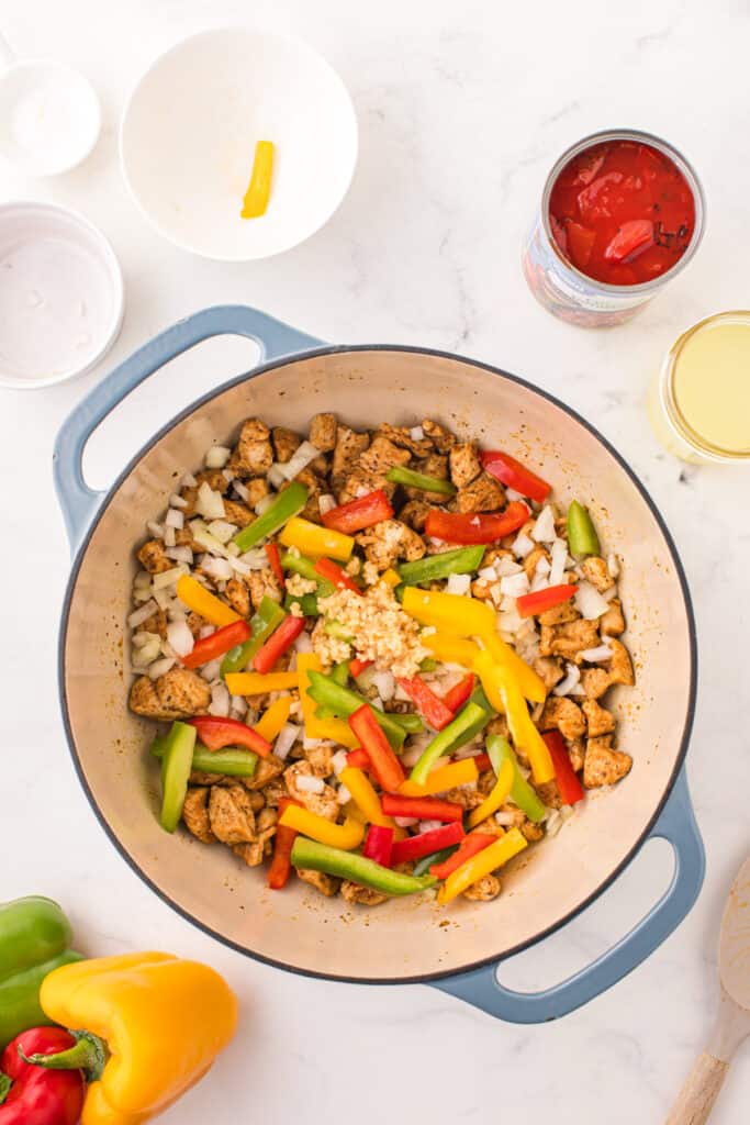 Colorful bell peppers, onion, and minced garlic added to seasoned chicken