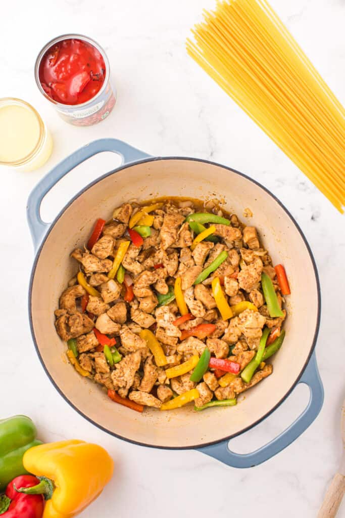 Chicken, bell peppers, and onions sautéing together before adding linguine