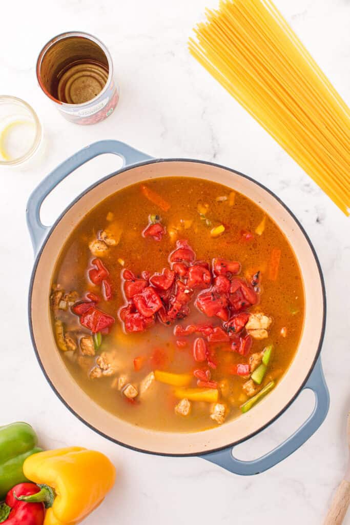 Fire-roasted tomatoes and chicken broth added to seasoned chicken and bell peppers