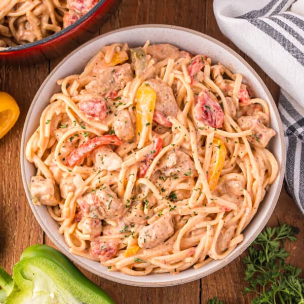 Creamy Cajun pasta with chicken, linguine, colorful bell peppers, tomatoes, and parsley in a serving bowl