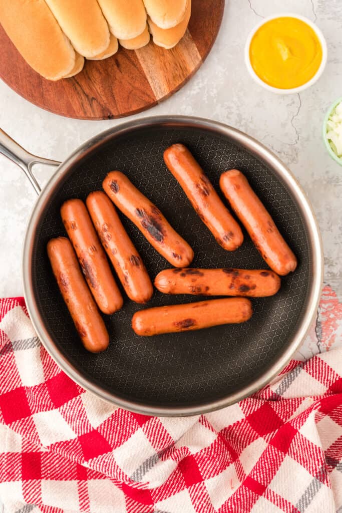 Hot dogs browned in a skillet before assembling Carolina Dogs.