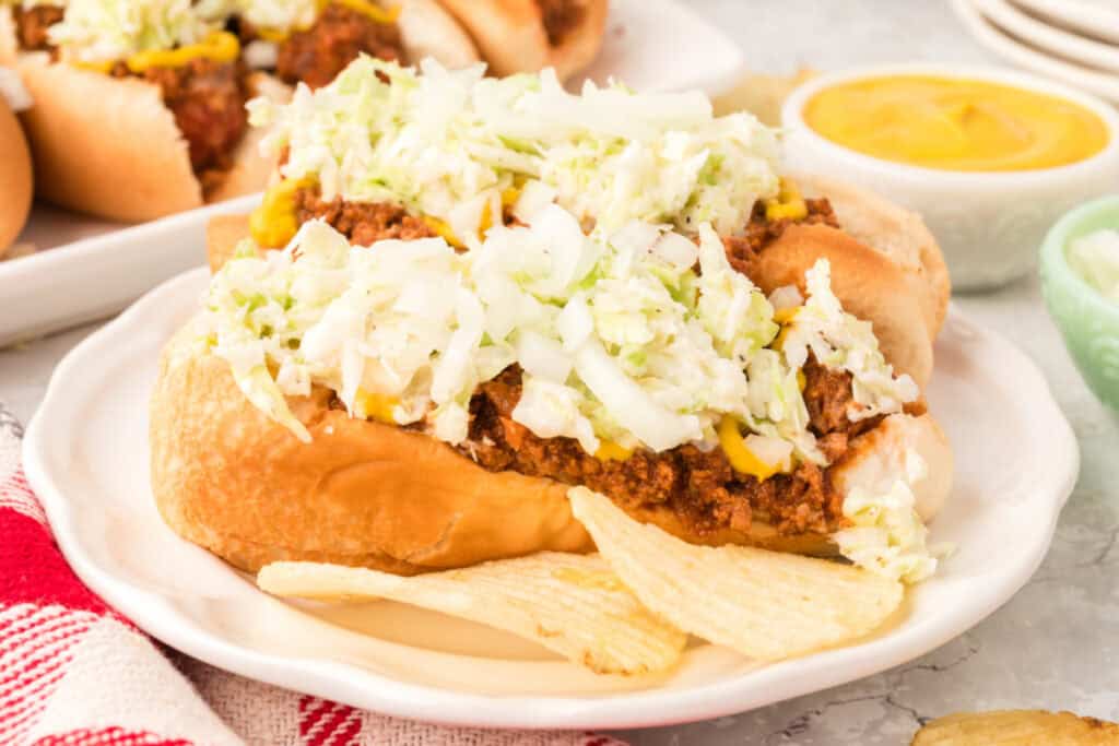 Close-up of Carolina Dogs topped with homemade chili, creamy slaw, chopped onions, and yellow mustard.