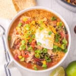 Bowl of easy Chicken Taco Soup topped with shredded cheddar cheese, sour cream, and green onions.