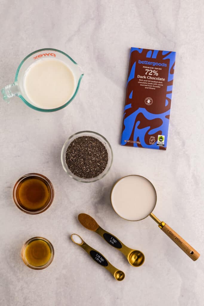 Ingredients for homemade Chocolate Chia Pudding including chia seeds, dark chocolate, cream, almond milk, maple syrup, vanilla, cinnamon, and salt