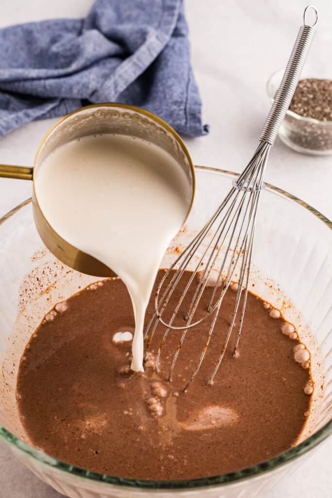 Cold almond milk being poured into the chocolate mixture before adding chia seeds